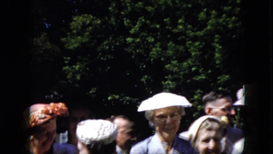 The final 1969 California 8mm frame shows adults in hats and suits at an outdoor gathering, partly cropped by the home-movie camera with leafy trees behind them.