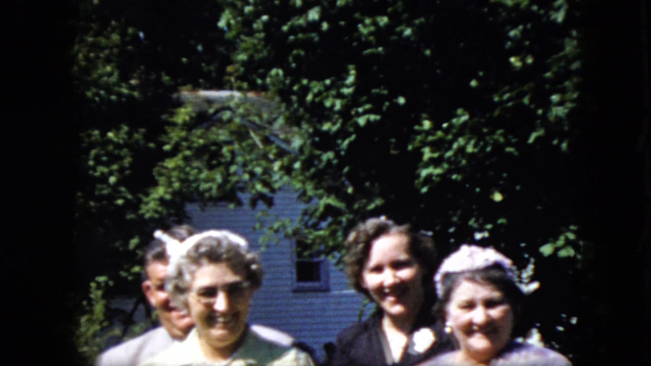 Adults smile toward the camera during an outdoor gathering.