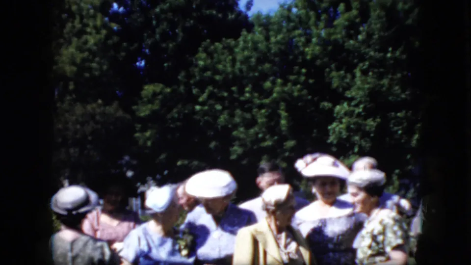 Adult women in formal dresses and brimmed hats appear outdoors in California in 1969, standing close together as they prepare for a group picture.