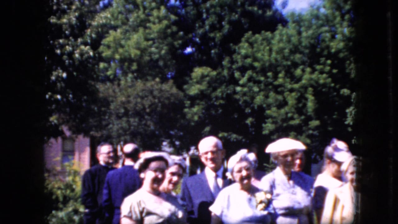 Group of adults standing outdoors behind a priest-like figure.