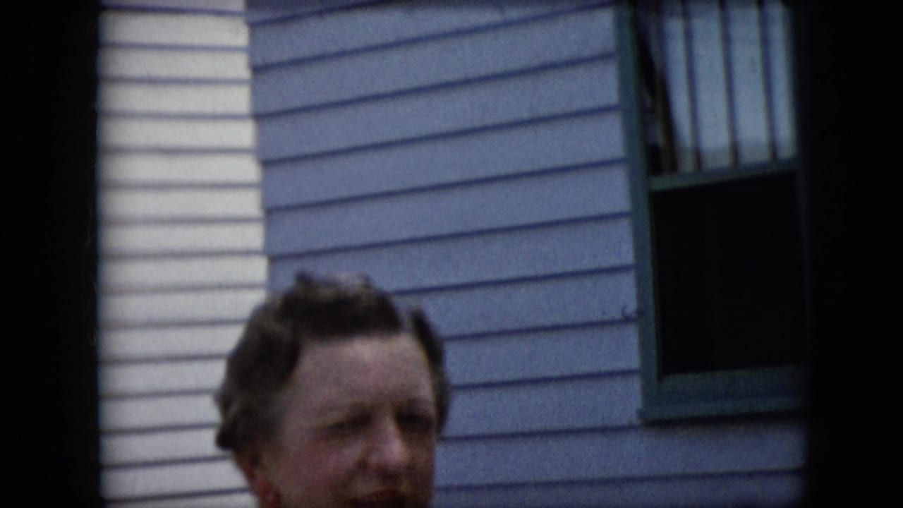 Woman's face partly framed in front of a light-sided house.