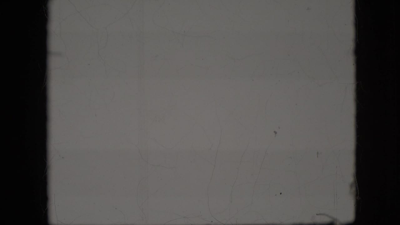 Faded 1969 8mm home-movie frame from the California reel, mostly overexposed with dark gate borders, dust, and faint surface marks but no clear subject visible.