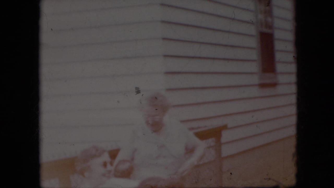 Soft, faded frame of a residential exterior with an indistinct figure near a railing.