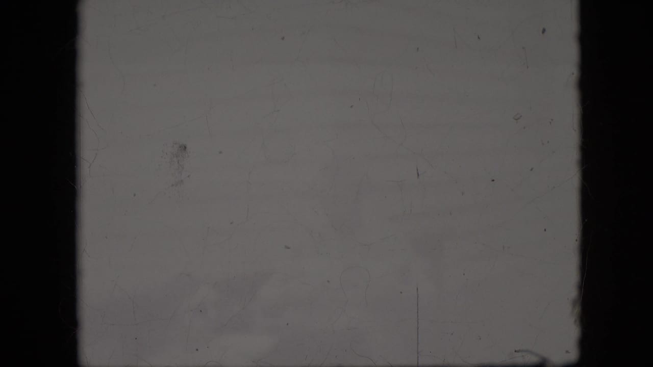 Mostly blank, scratched film frame with faint exposure and dark borders.