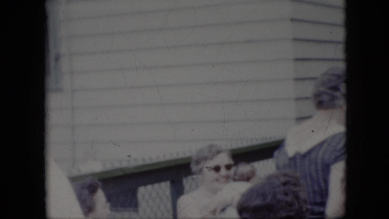 Woman in sunglasses smiles near a porch railing and other adults.