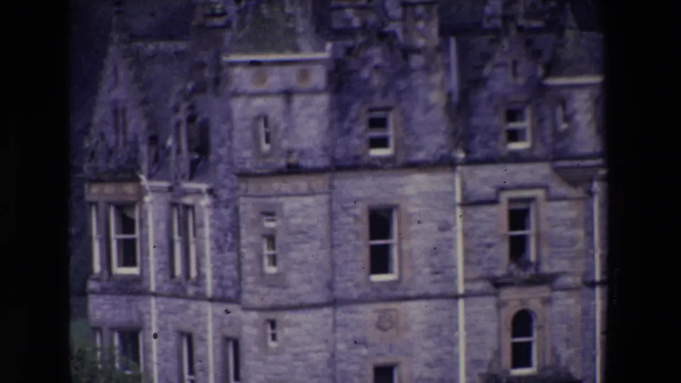 Soft 8mm view of a large stone building in Ireland, with windows and weathered masonry visible through dark frame edges.