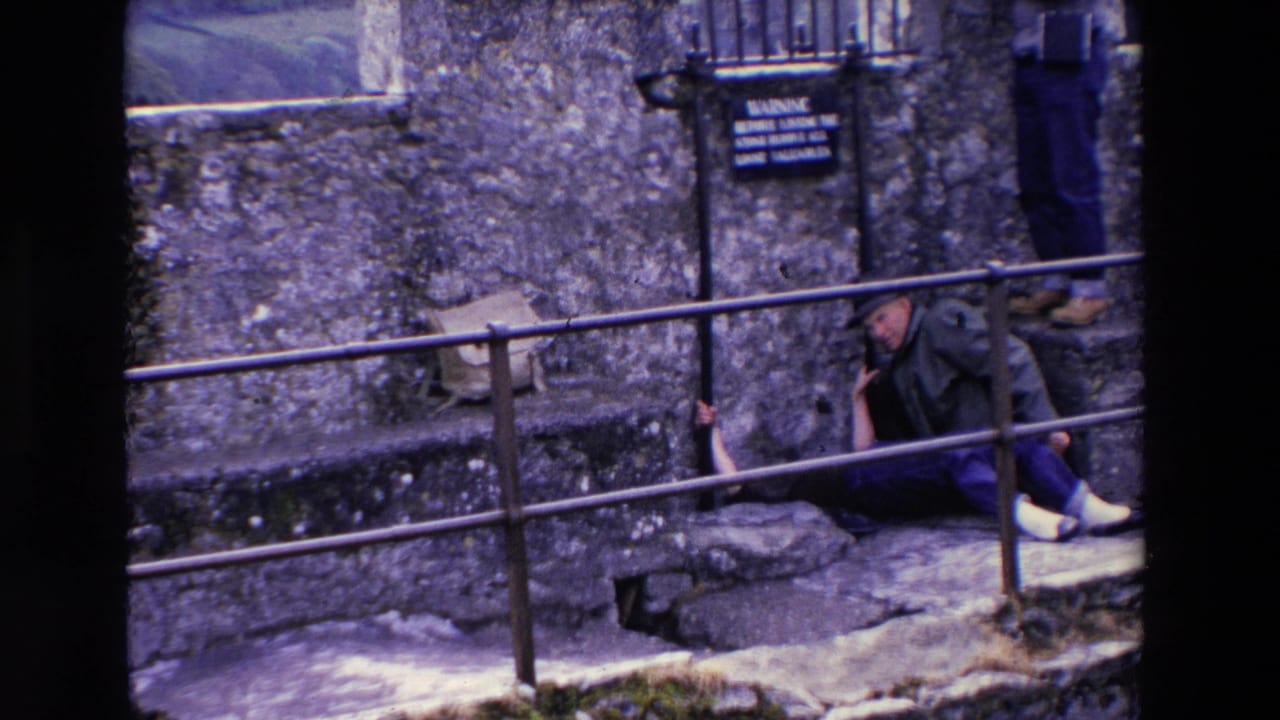 Older couple seated and reclining on stone steps by a railing.