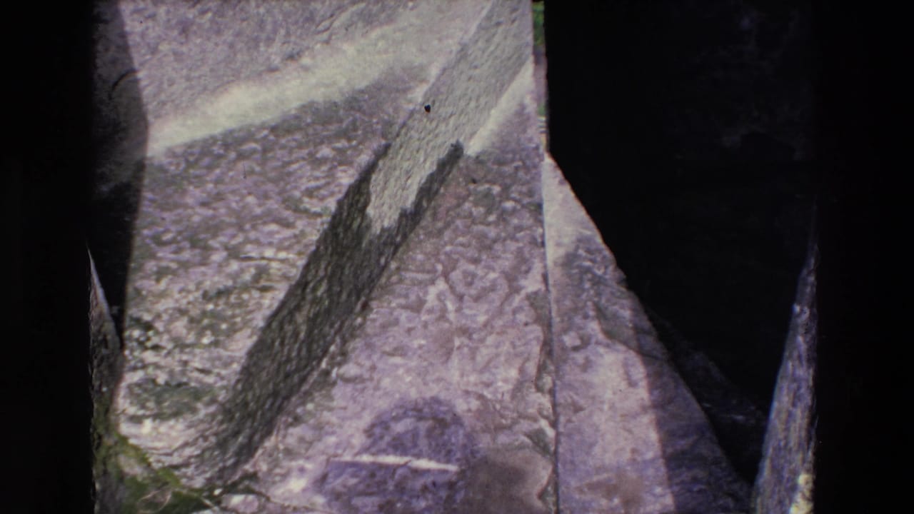 Rock face and steep dark gap seen from above in a handheld mountain view.