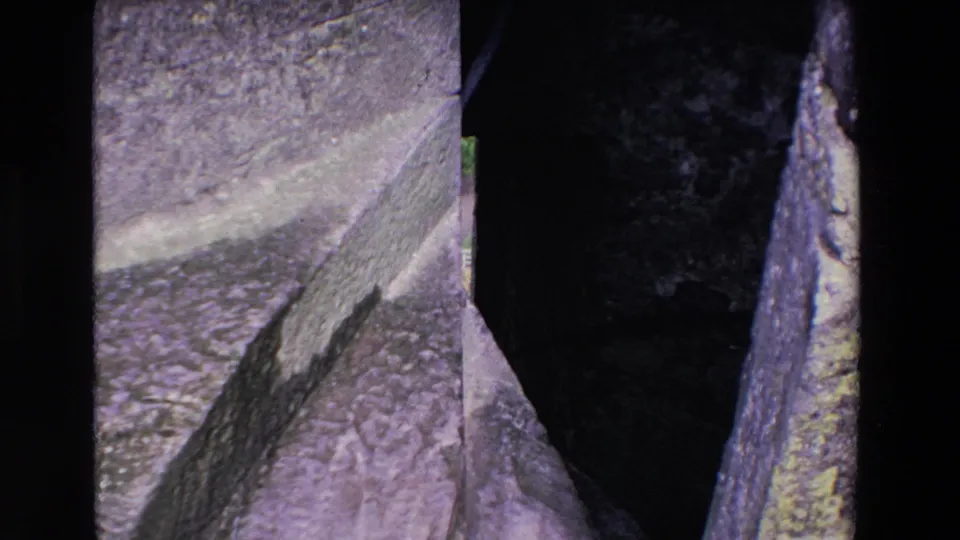 1969 Ireland 8mm frame looking across a close section of mountain rock, showing a dark crevice, rough stone planes, and aged home-movie color shift.