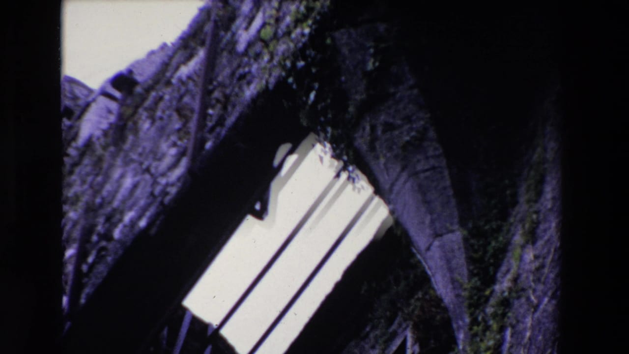 Closer tilted view of a stone arch opening with vertical bars and dark masonry.
