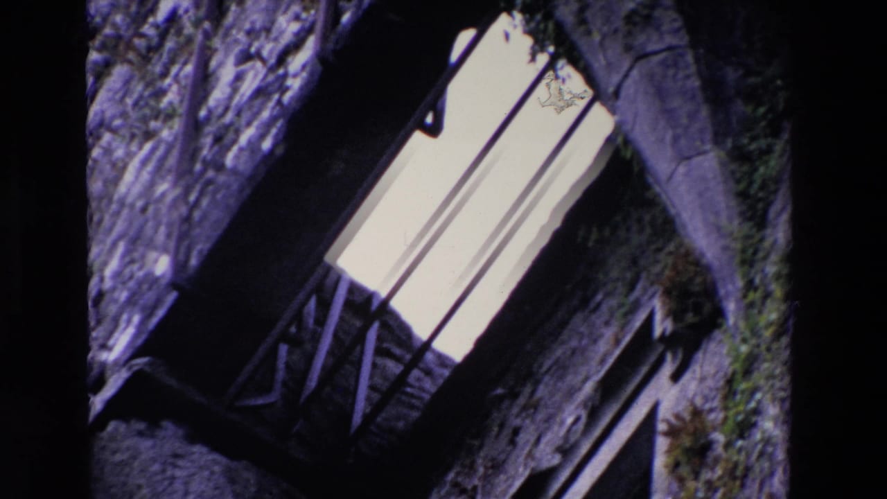 Close angled view of rough stonework and a bright window with bars.