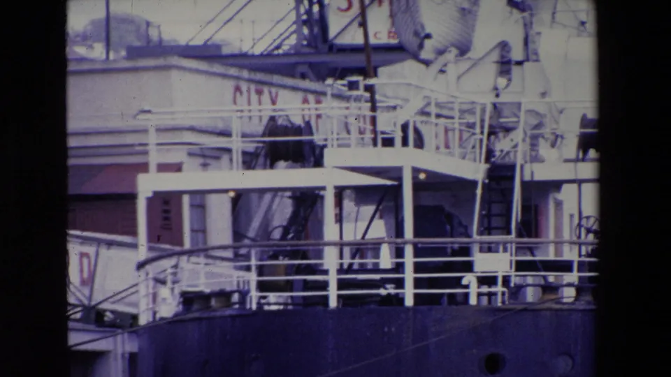 1969 Ireland 8mm frame showing upper structures of the docked INNISFALLEN, including railings, ladder, lifeboat equipment, and part of the blue hull.