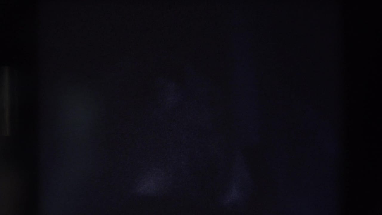 Dark, grainy 8mm frame from the clip with no clearly identifiable person or object visible.