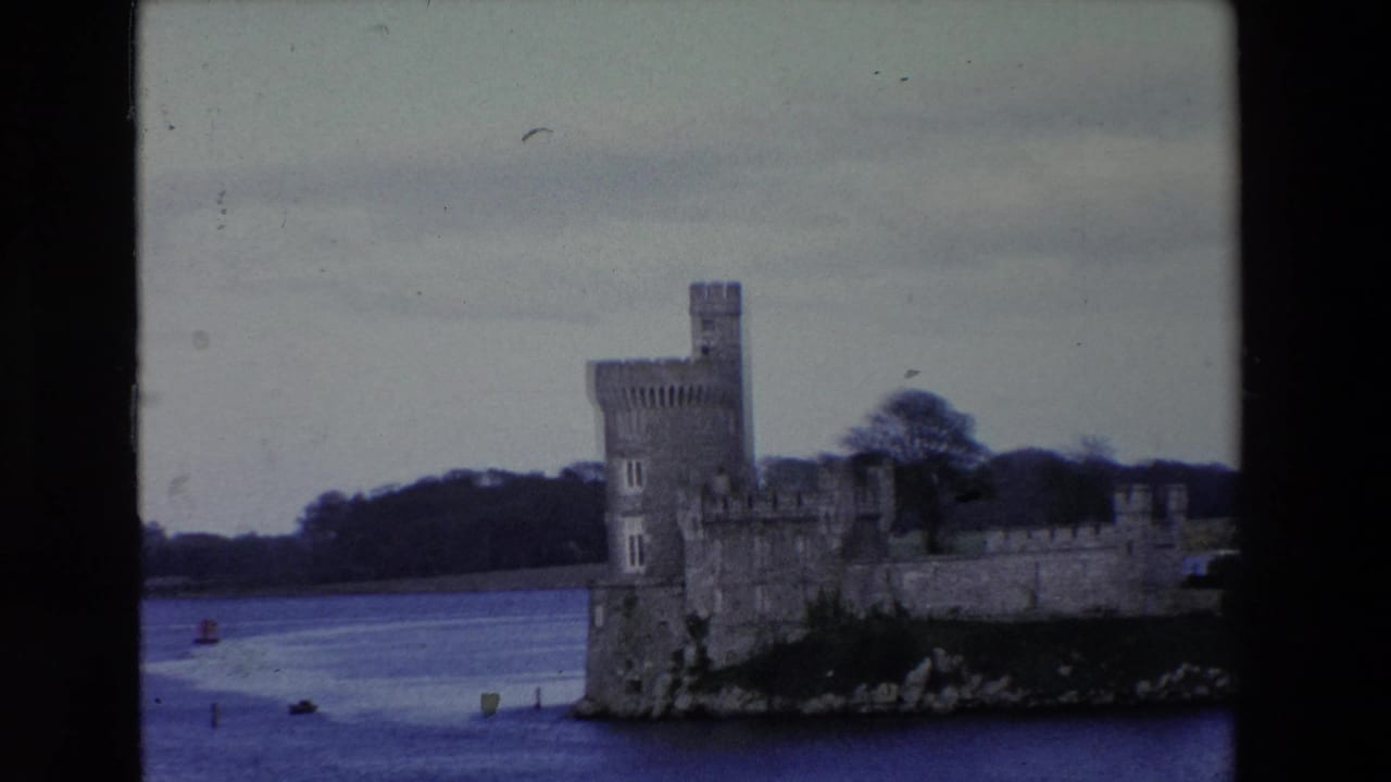 Castle on the river with small boats or markers visible in the water.