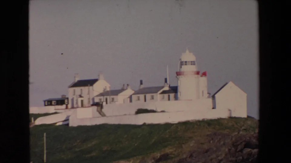 1969 Ireland frame showing the lighthouse tower and adjoining whitewashed structures more prominently on the grassy coastal outcropping.