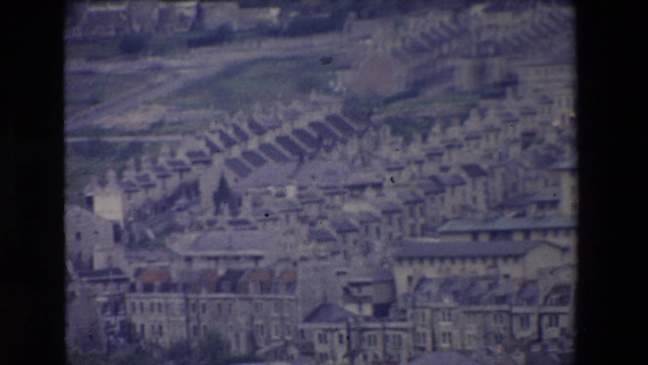 Soft distant view of town buildings, rooftops, and a church spire on a hillside.