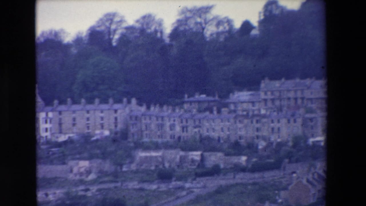 Row houses and larger buildings stretch across a wooded slope.