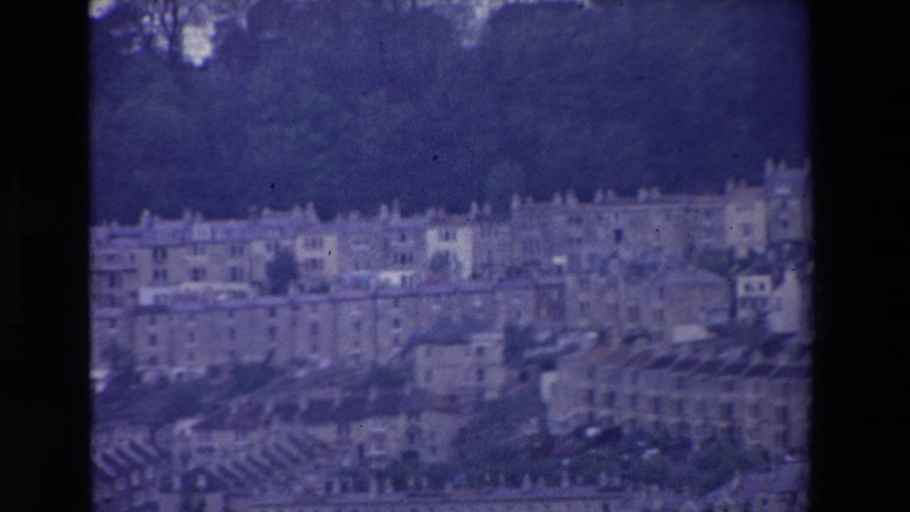 Long rows of hillside buildings with trees above them.