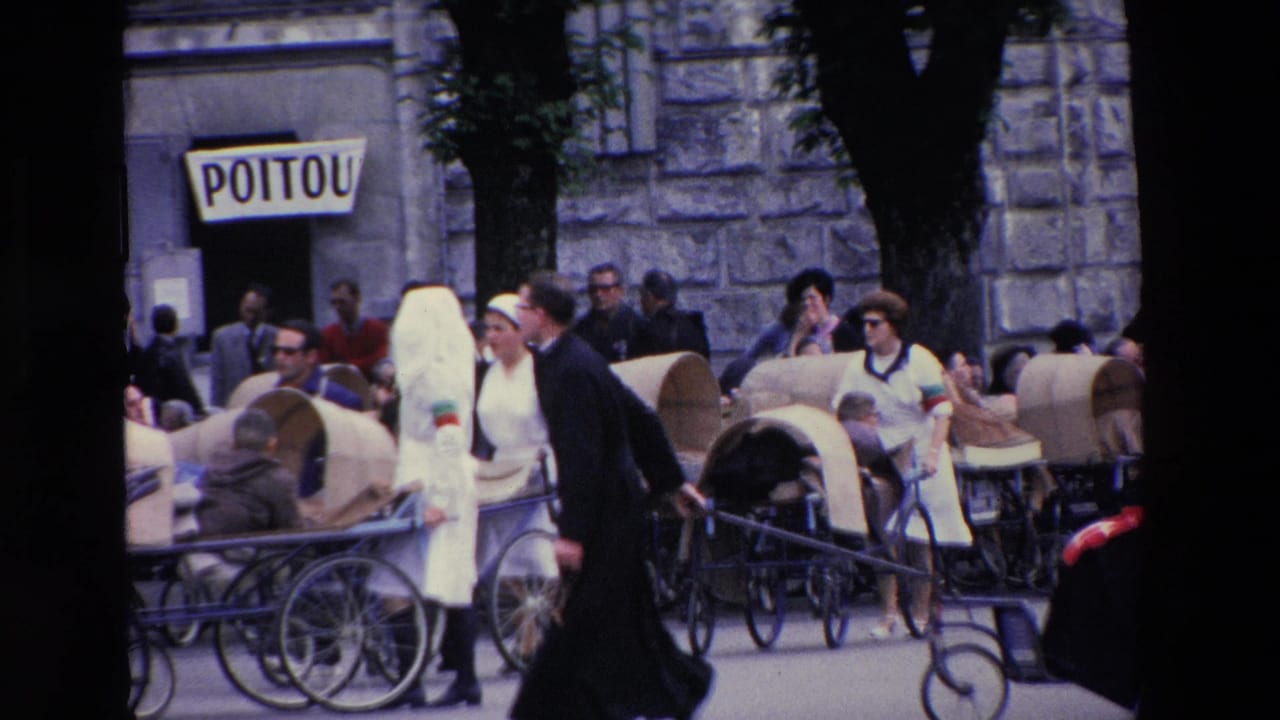 In Lourdes, France, according to the clip metadata, nuns and attendants move covered wheeled carts carrying elderly or infirm pilgrims along a stone-walled street in 1969.