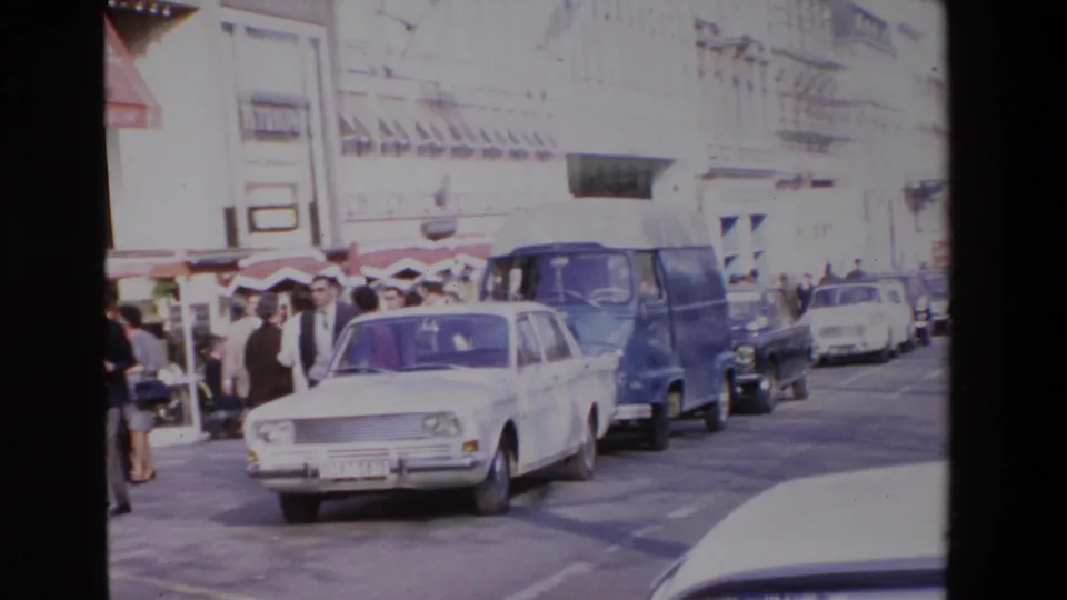 A French street scene from the supplied 1969 metadata shows a white sedan, blue van, pedestrians, awnings, and storefronts along a busy curb.