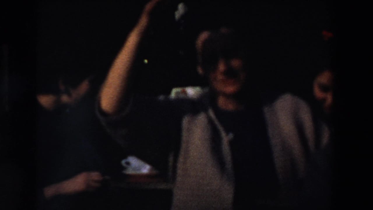 Dark, underexposed 8mm frame showing partially visible people near a shadowed opening during the same 1969 France home-movie sequence.