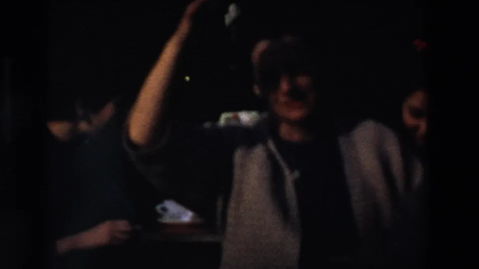 Dark, underexposed 8mm frame showing partially visible people near a shadowed opening during the same 1969 France home-movie sequence.
