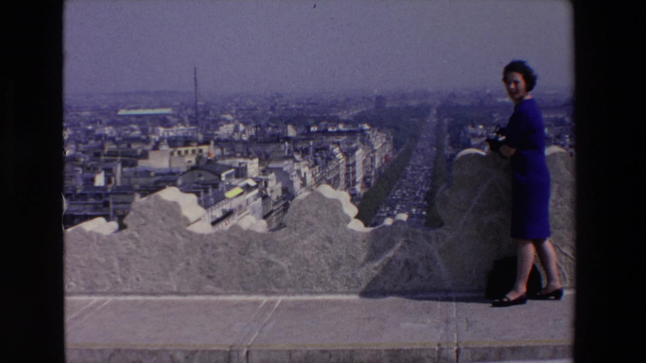 Woman in a blue dress poses on a stone observation deck above a city.