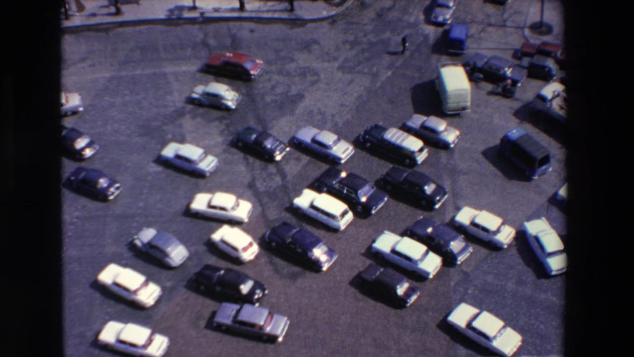 Elevated view of a parking lot filled with parked 1960s-era cars.