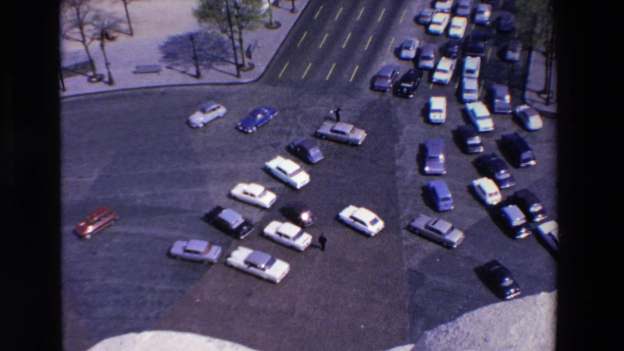 Elevated 8mm frame of roundabout traffic in the France location identified by metadata, showing clustered cars, a few pedestrians, and sidewalks around the intersection.