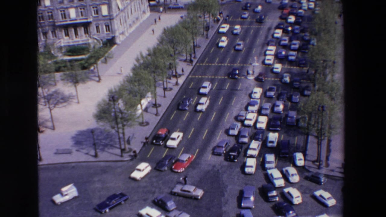 Elevated view of cars moving through a busy tree-lined city road junction.