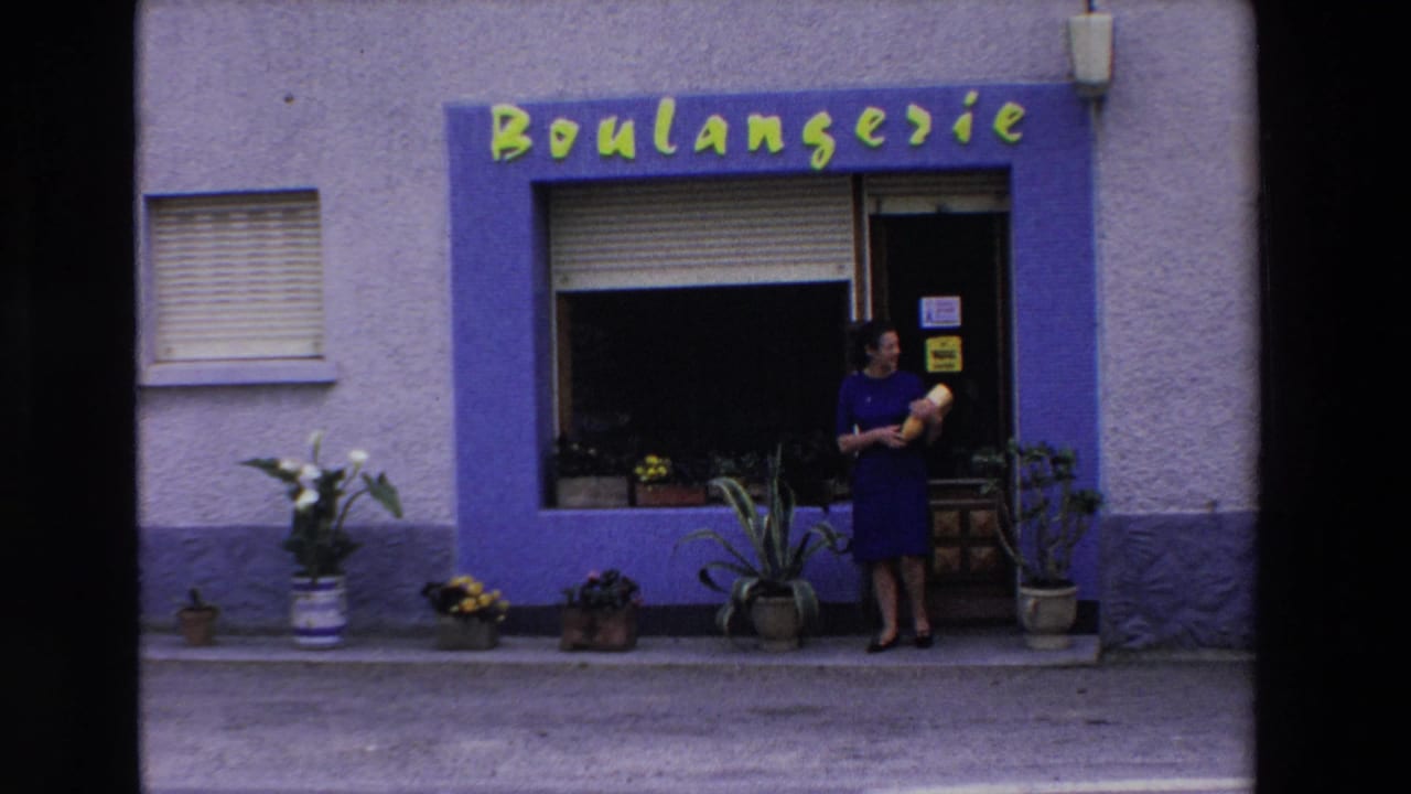 Woman in a blue dress standing outside a boulangerie with yellow lettering.