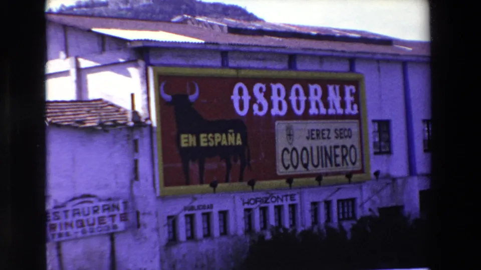 A building wall carries a large Osborne sherry advertisement with a bull graphic and visible Spanish wording, including En España and Jerez Seco Coquinero, in the supplied 1969 European street footage.