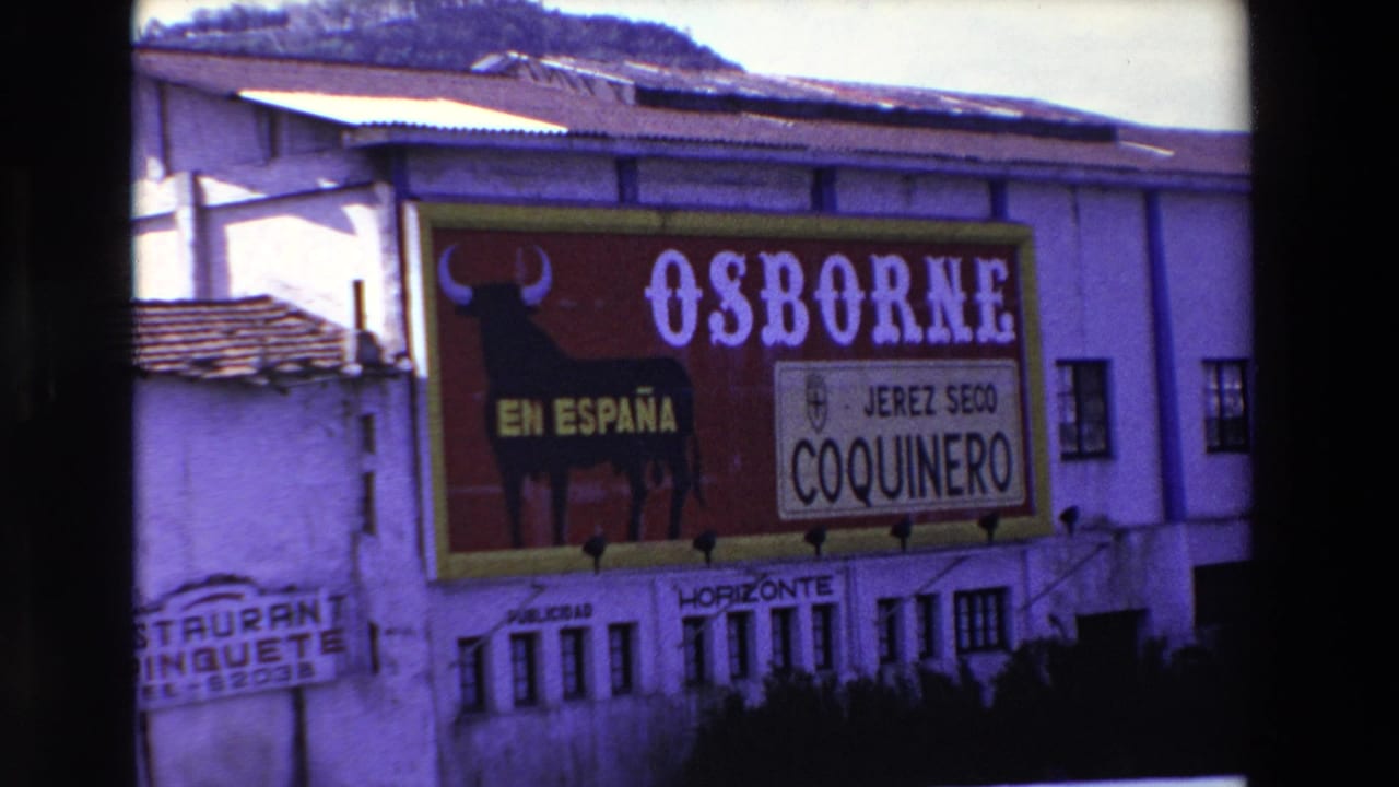 1969 Lourdes, France 8mm frame showing a large red Osborne sign on a white building, with a black bull silhouette, EN ESPAÑA text, and JEREZ SECO COQUINERO branding.