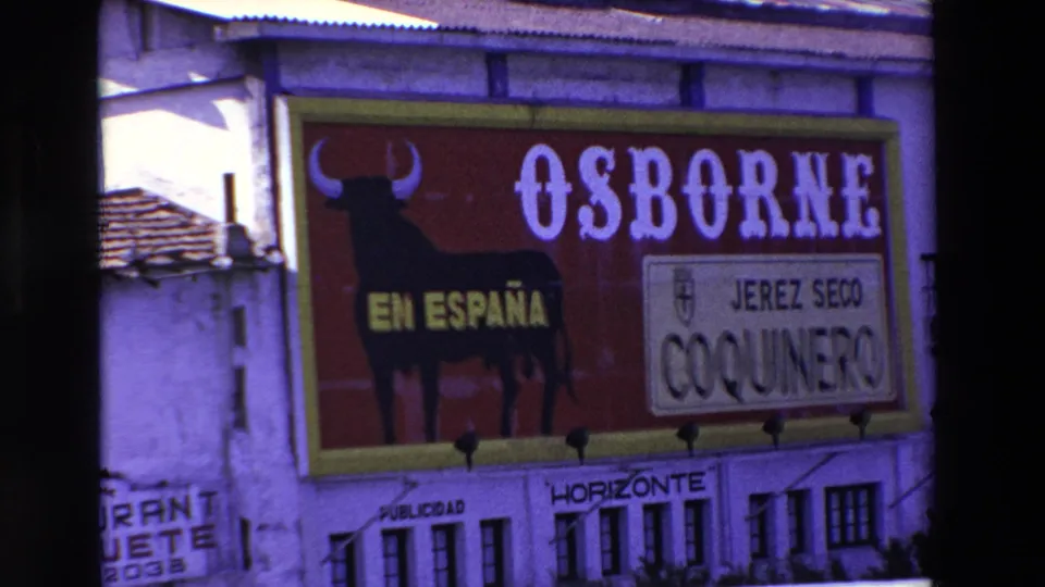 1969 Lourdes, France 8mm frame with a closer crop of the Osborne lettering, bull silhouette, EN ESPAÑA text, and JEREZ SECO COQUINERO panel on a white building facade.