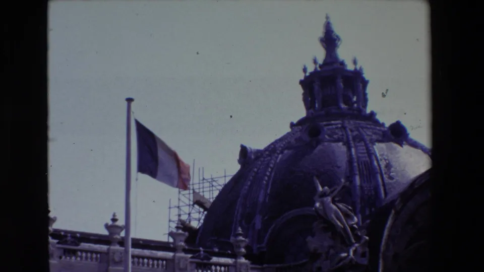 1969 Paris 8mm frame moving closer on the half-mast French flag, domed roof, sculptural decoration, and repair scaffolding.