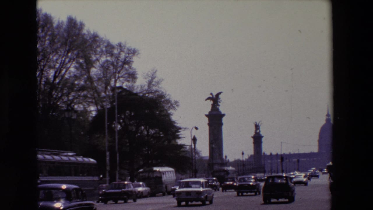 Traffic and a bus move along a Paris avenue framed by dark 8mm film borders.