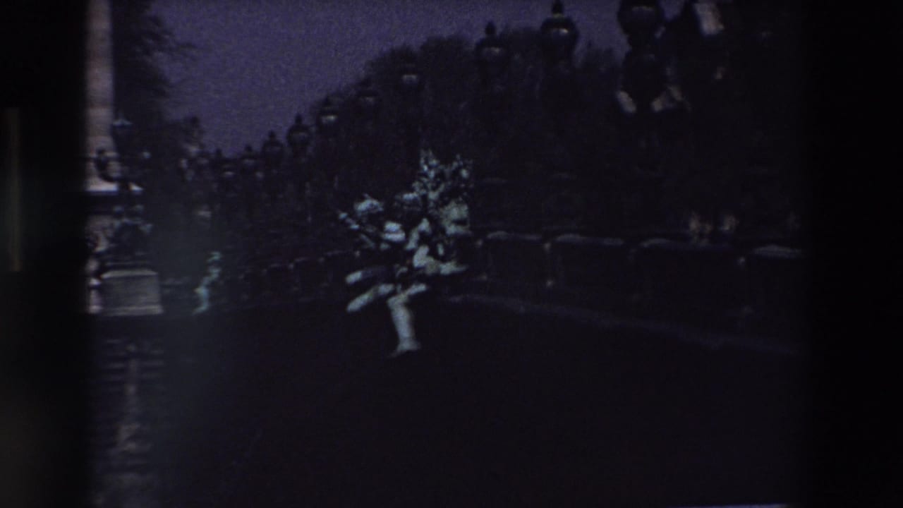 Stone figure stands out in low light with trees and lampposts behind it.