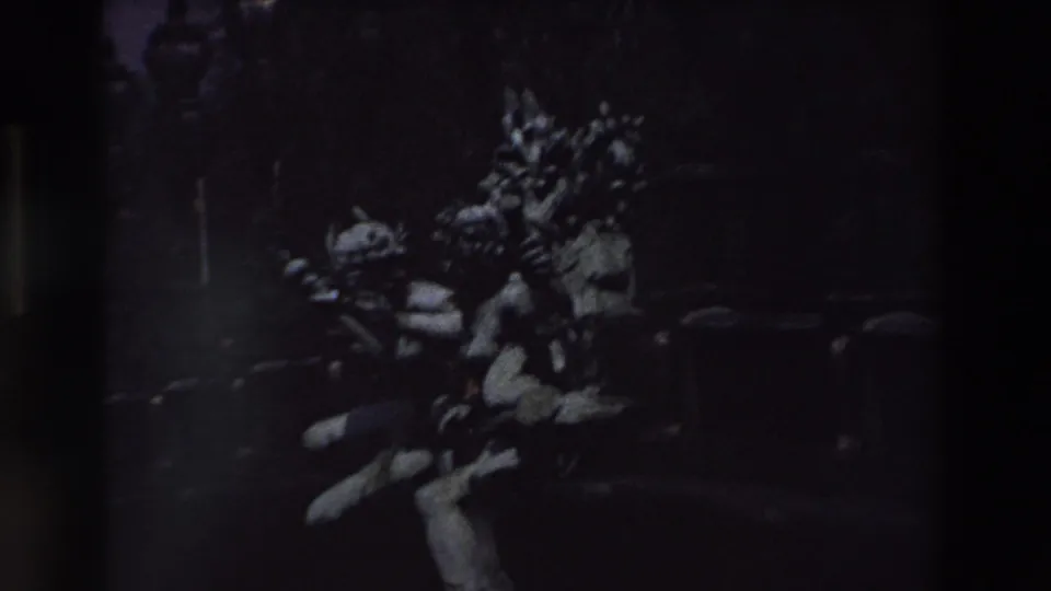 1969 Paris frame showing the statue or sculptural group larger in the frame, its pale stone forms visible against dense darkness, trees, and faint urban lighting.