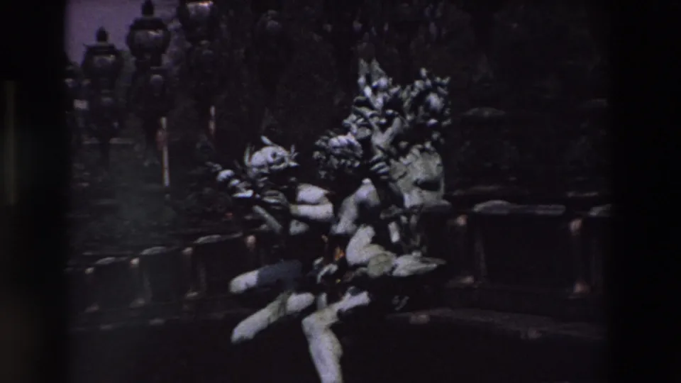 Dark 8mm frame from Paris showing sculptural figures and ornate lamps partly obscured by heavy shadow and a vertical film or camera edge.