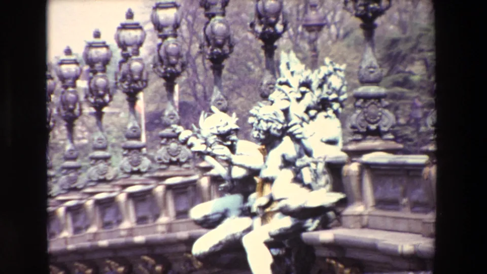 Brighter 1969 Paris frame showing pale patinated statuary, elaborate lamp posts, bare trees, and carved stone bridge or monument details.