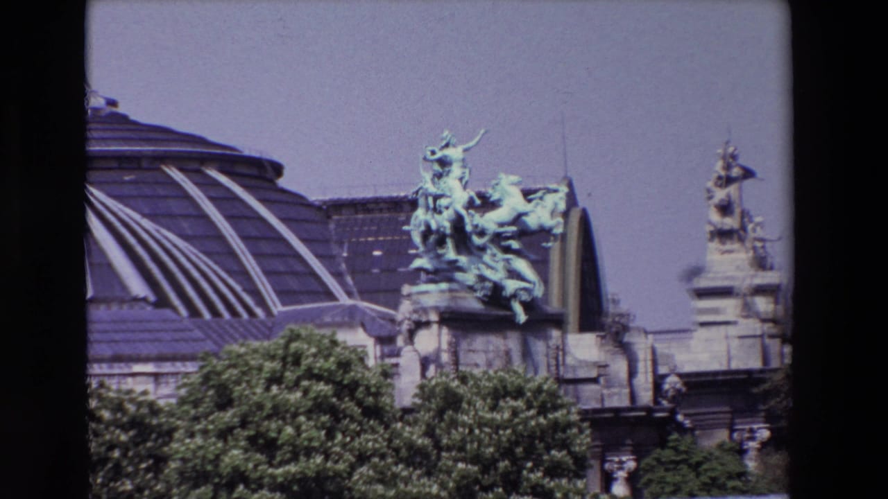 1969 Paris 8mm frame showing a green-patinated equestrian sculpture on a grand stone building, with a glass roof and trees below.