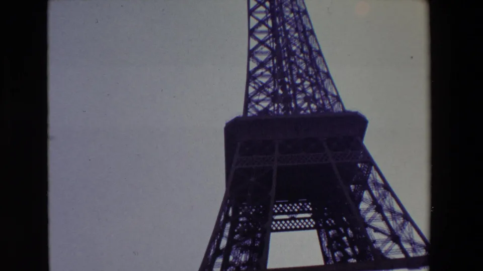 1969 Paris travel frame with the Eiffel Tower rising through the right side of the image, its platform and ironwork silhouetted against the sky.