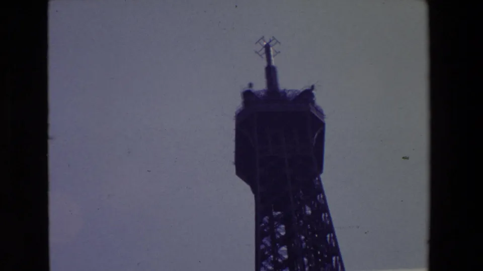 1969 Paris frame with the Eiffel Tower summit silhouetted near the right side, showing the antenna mast and upper lattice detail against open sky.