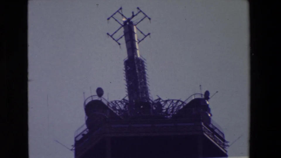 Tight 1969 Paris frame of the Eiffel Tower summit, showing the antenna mast and cross-shaped aerial elements above the dark upper platform.
