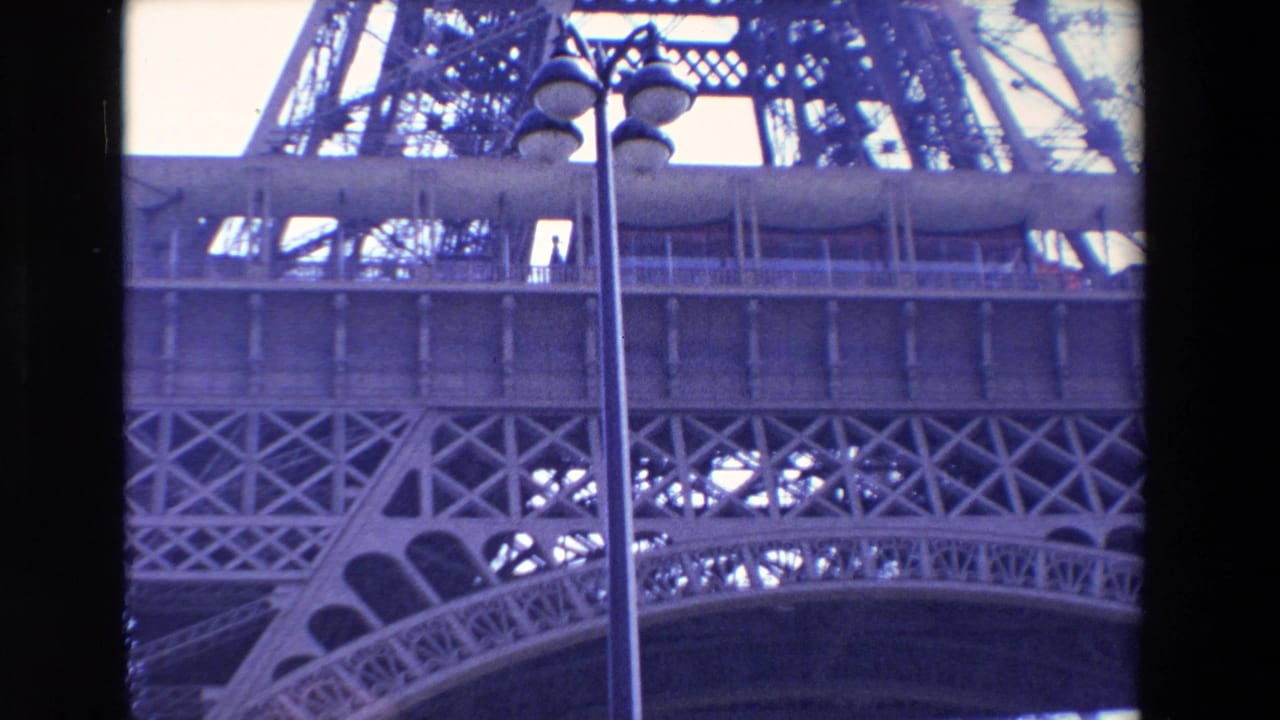 Closer low-angle view of Eiffel Tower lattice and platform with lamppost.