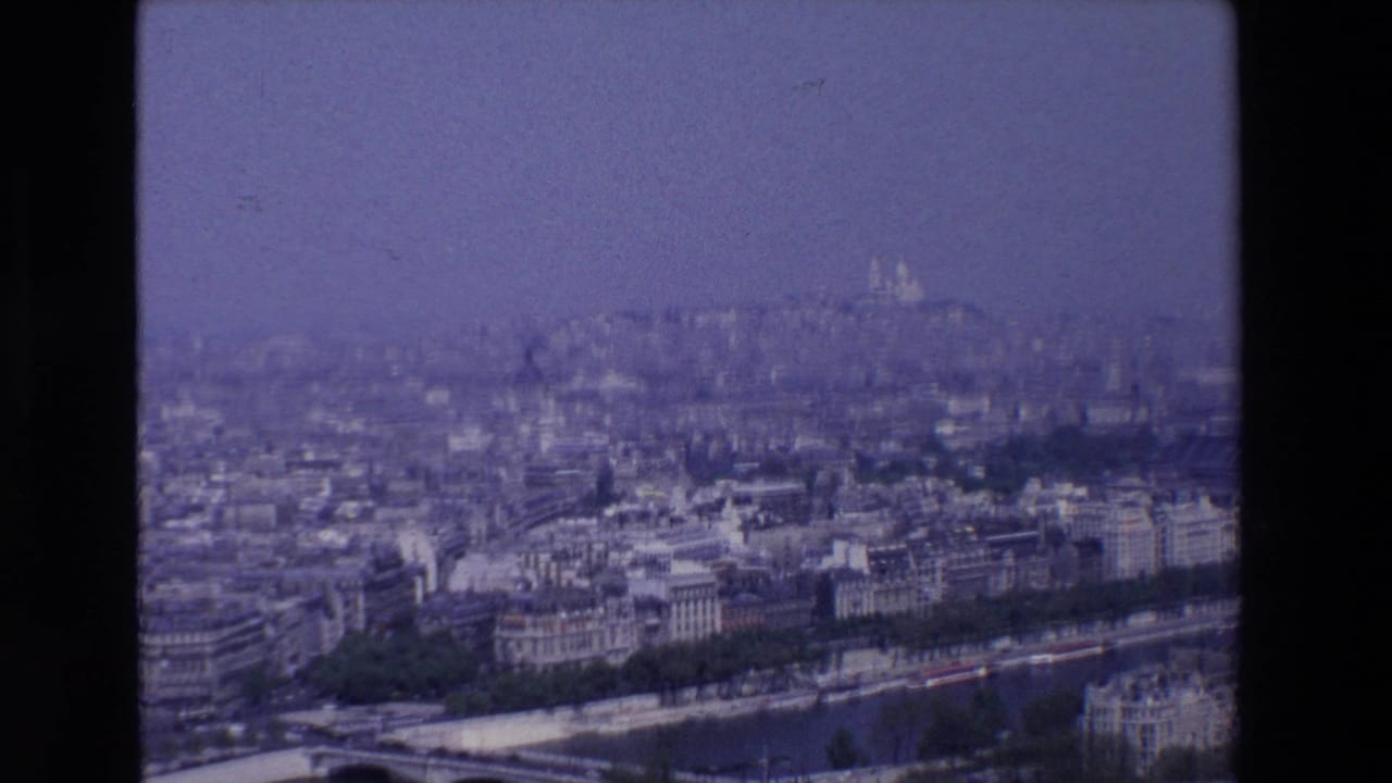 1969 Paris frame from an elevated visitor viewpoint, with the Seine and bridge in the foreground and Sacré-Cœur faintly visible in the haze.