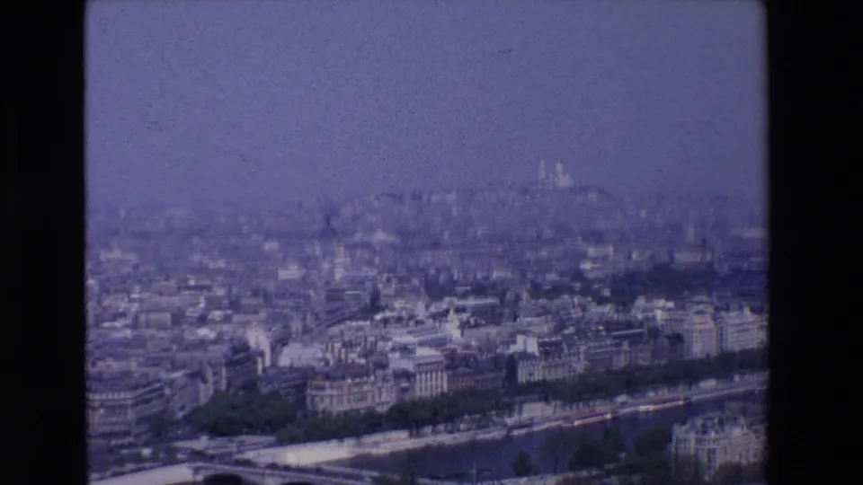 1969 Paris frame from an elevated visitor viewpoint, with the Seine and bridge in the foreground and Sacré-Cœur faintly visible in the haze.