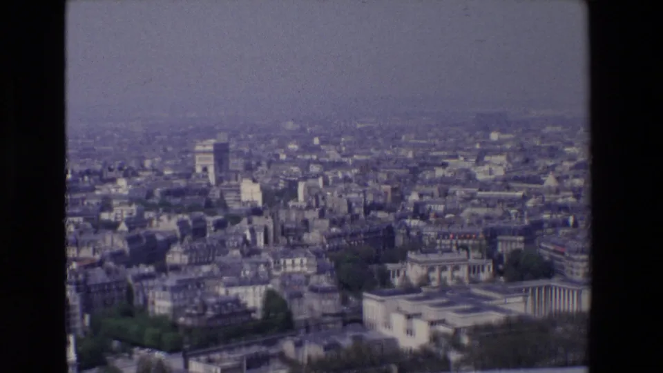 Elevated 1969 Paris panorama showing the Arc de Triomphe among dense rooftops, pale buildings, and a hazy urban horizon.