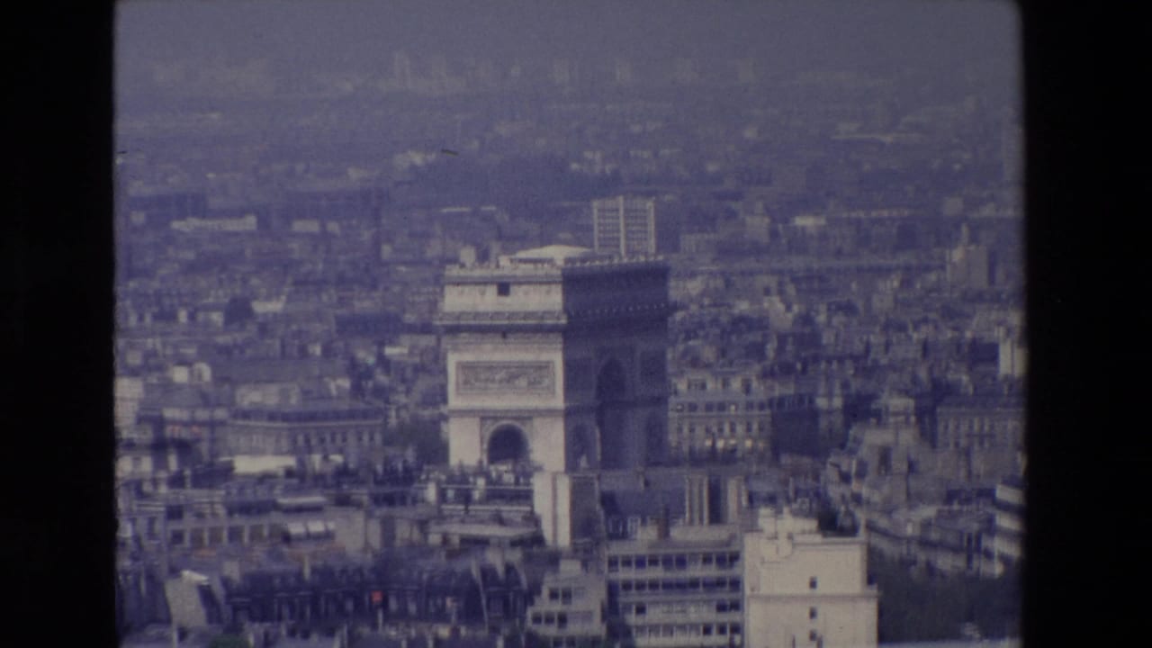 1969 Paris frame with the Arc de Triomphe more prominent in the center-right of a soft, grainy aerial city view.