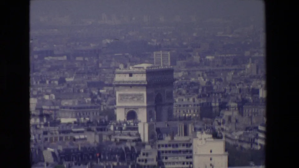 1969 Paris frame with the Arc de Triomphe more prominent in the center-right of a soft, grainy aerial city view.